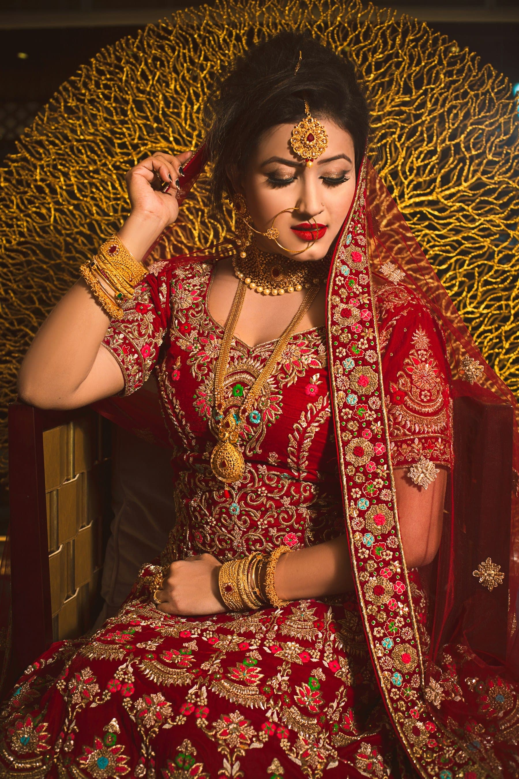 Bride in a red embroidered lehenga with gold jewellery