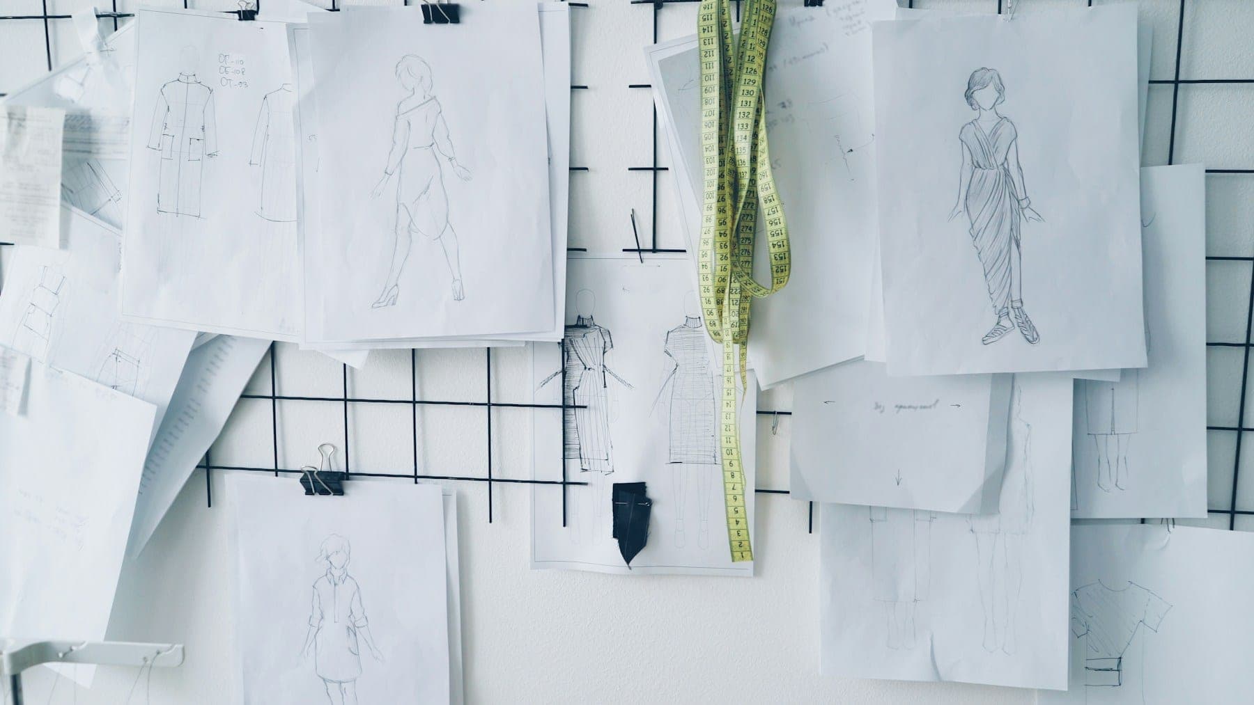 Fashion sketches pinned to a studio wall grid