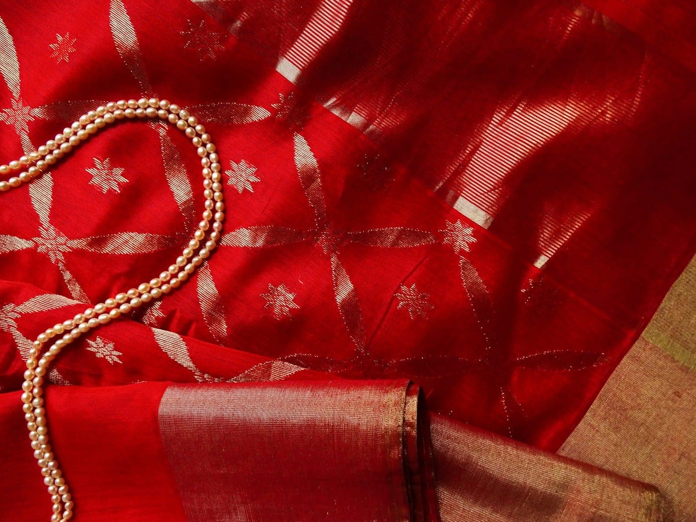 Close-up of red silk with woven gold motifs