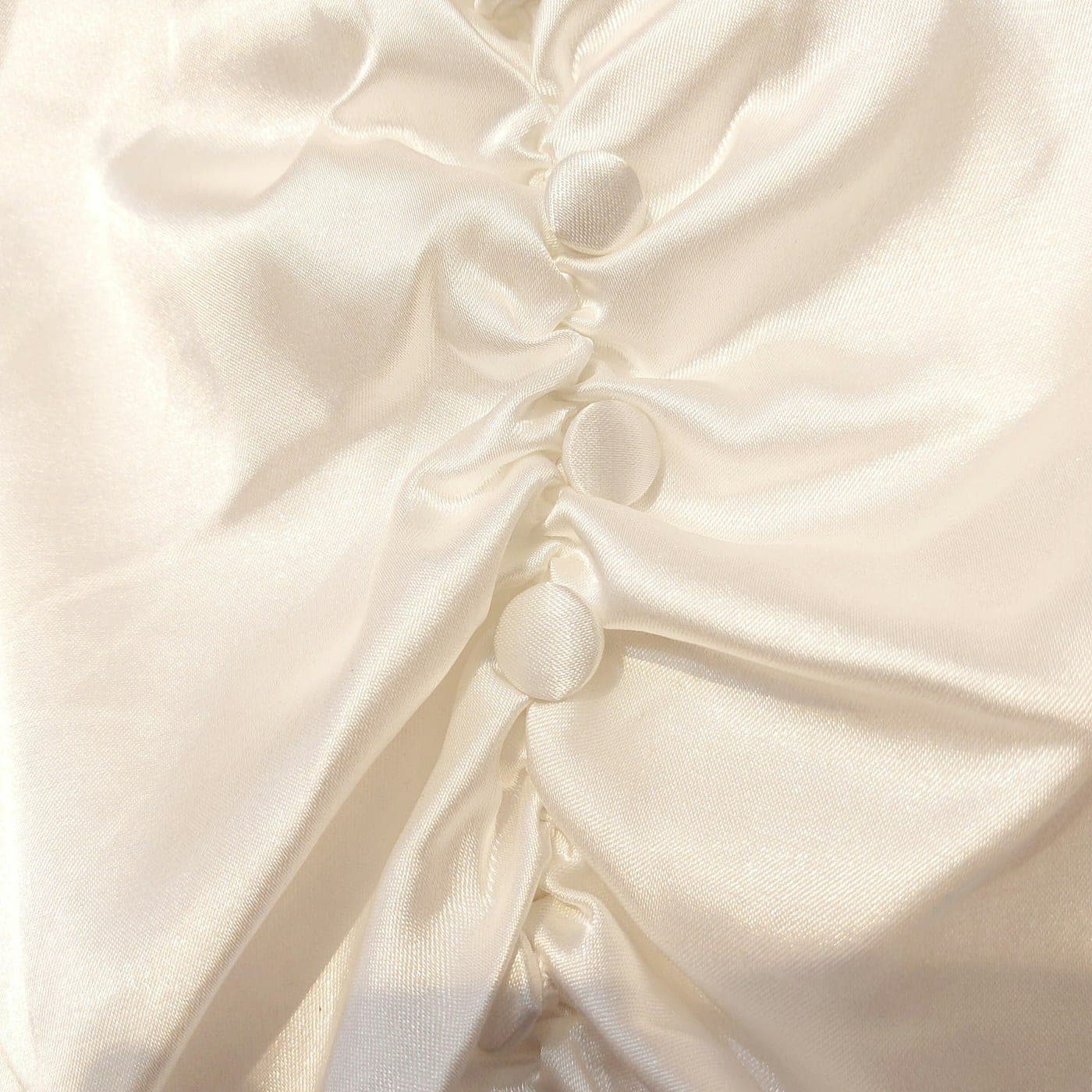 Close-up of ivory satin with covered buttons