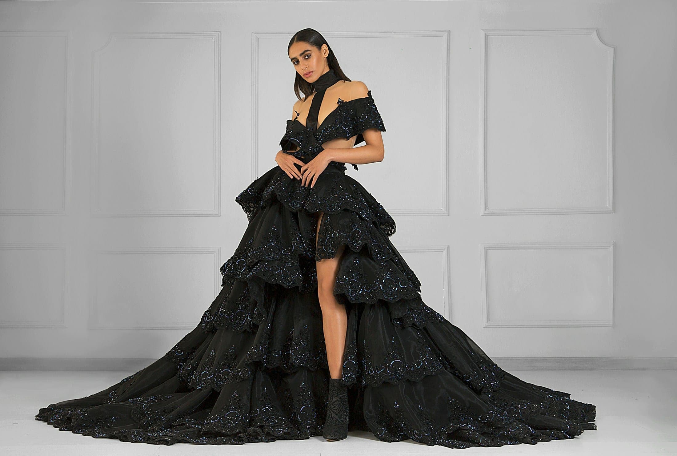 Model in a tiered black couture gown in a white studio